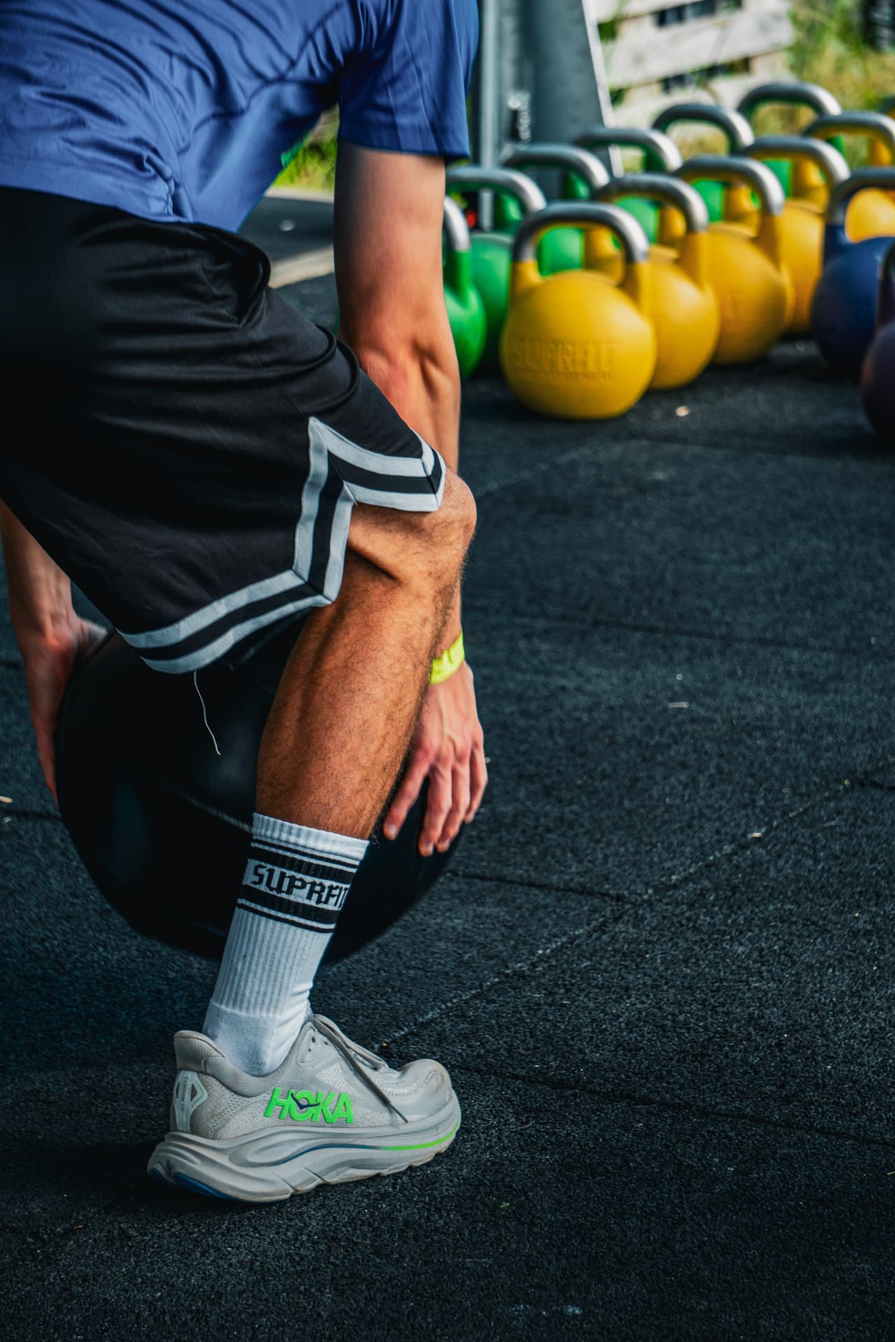 Athlet mit Suprfit-Socken am Medizinball vor einer Kettlebell-Reihe